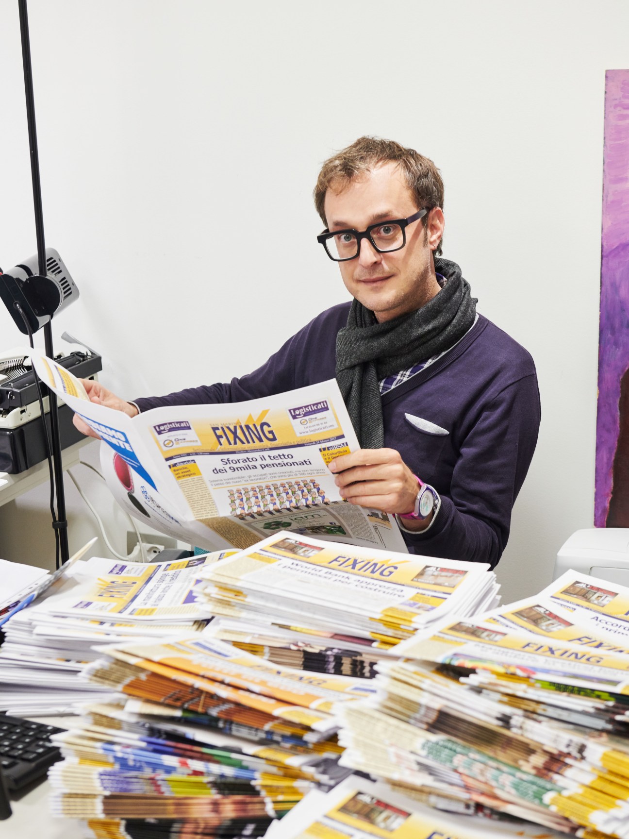 Alessandro Carli, editor of San Marino Fixing financial newspaper, reading a copy of the publication at his desk.