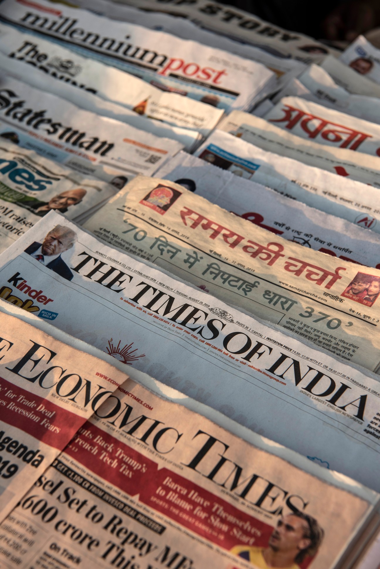 Stack of Times of India newspapers and other Indian publications displayed at a newsstand.
