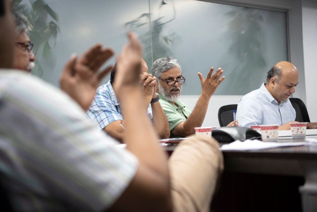 Shankar Raghuraman, senior editor with Times Insight Group, gestures while speaking at a newsroom meeting table.