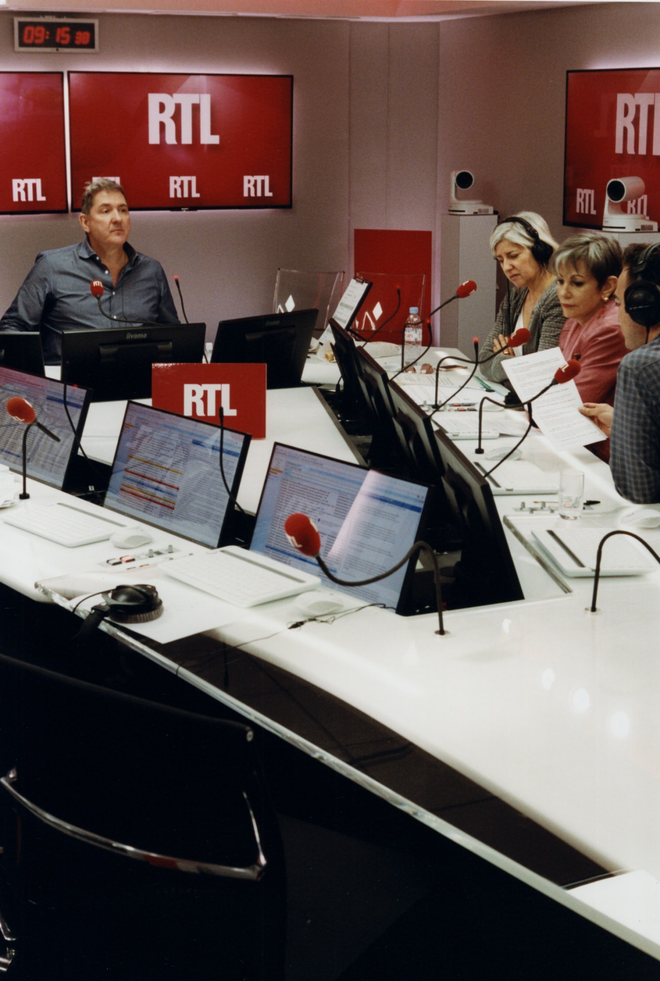 RTL morning host Yves Calvi and his team in the radio studio control room with microphones and monitors.