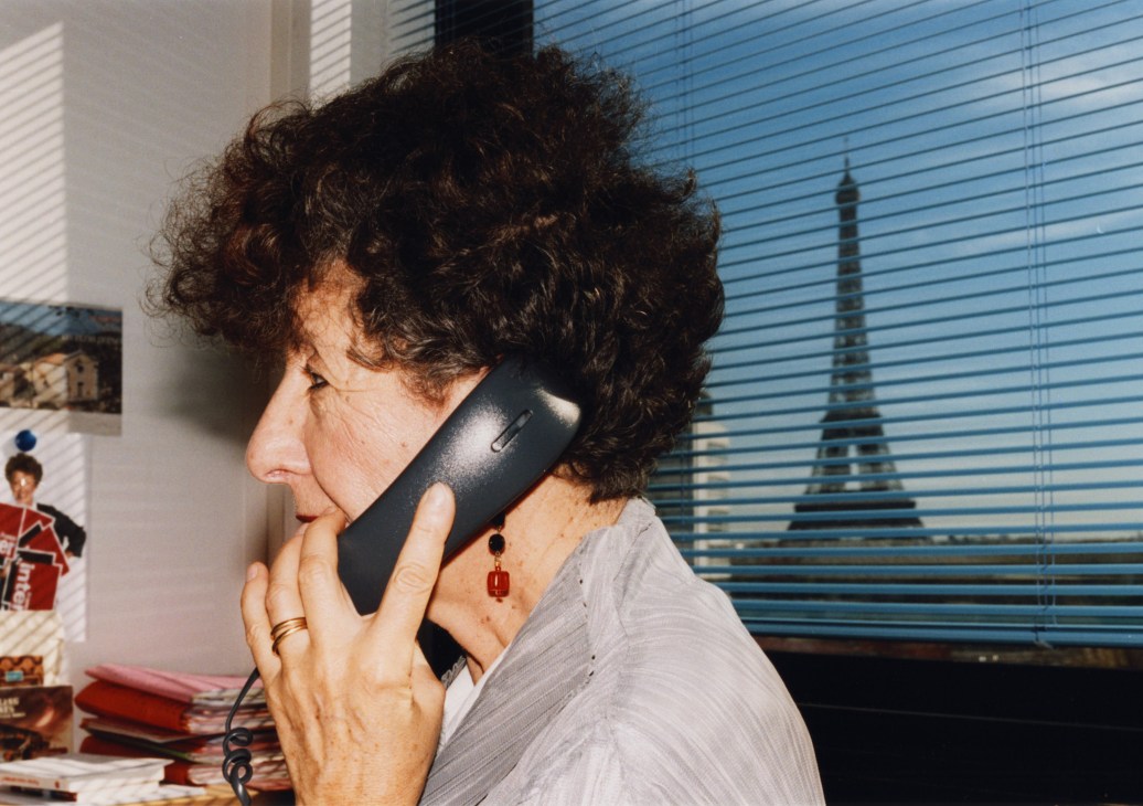 Laurence Bloch, France Inter director, speaking on a phone with Eiffel Tower visible through office window