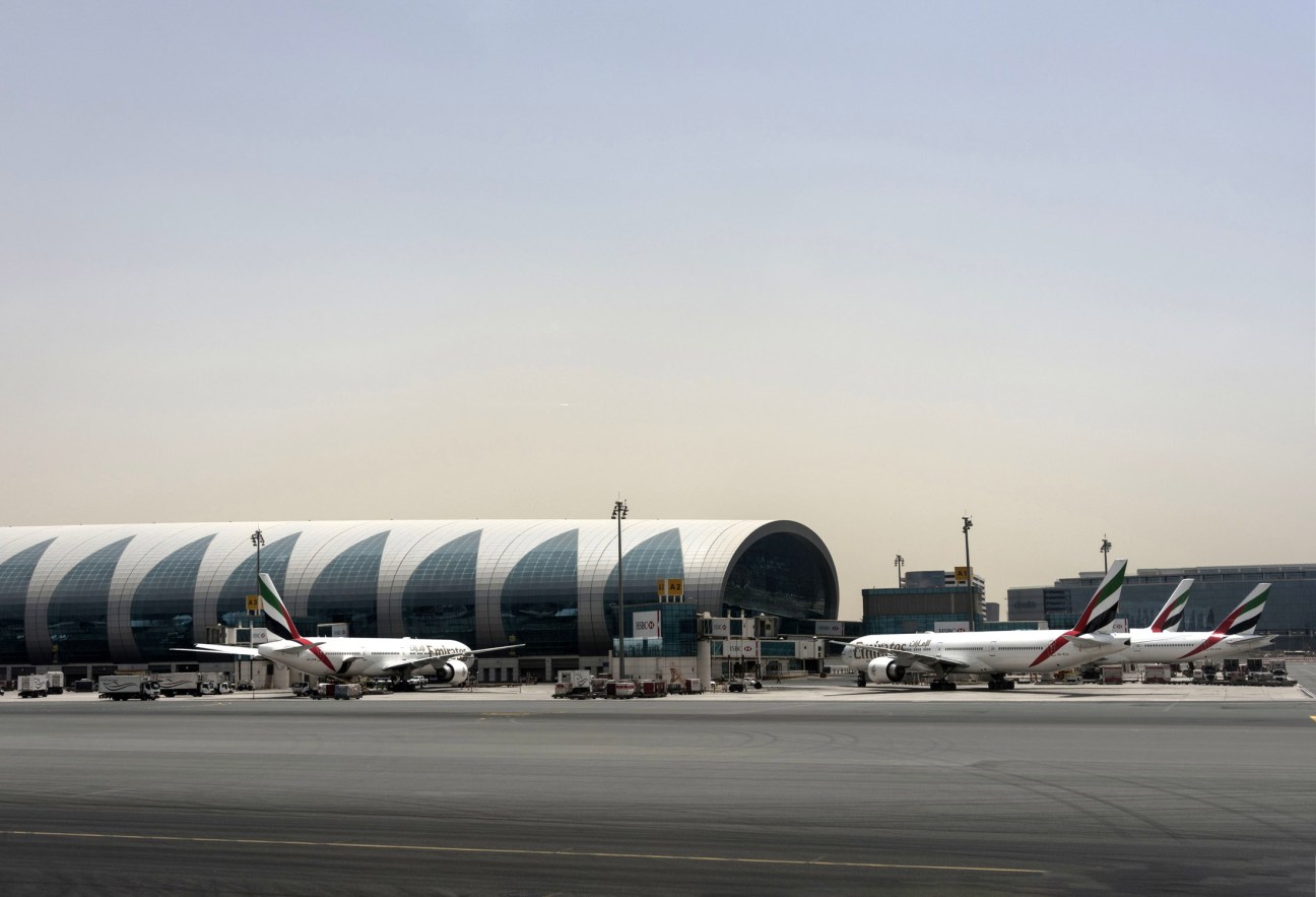 Emirates aircraft parked on tarmac at Dubai airport with distinctive terminal building
