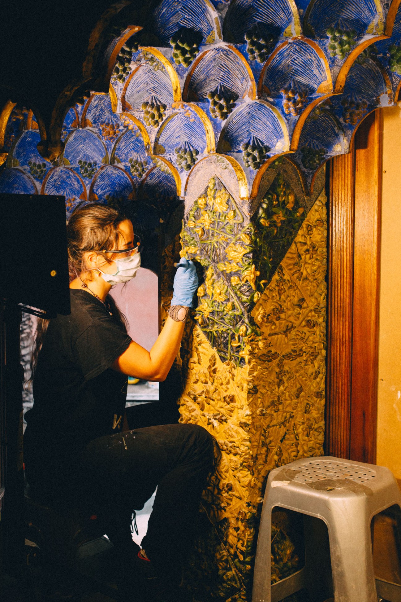A restoration specialist in protective gear works on ornate blue and yellow tilework at Casa Vicens.