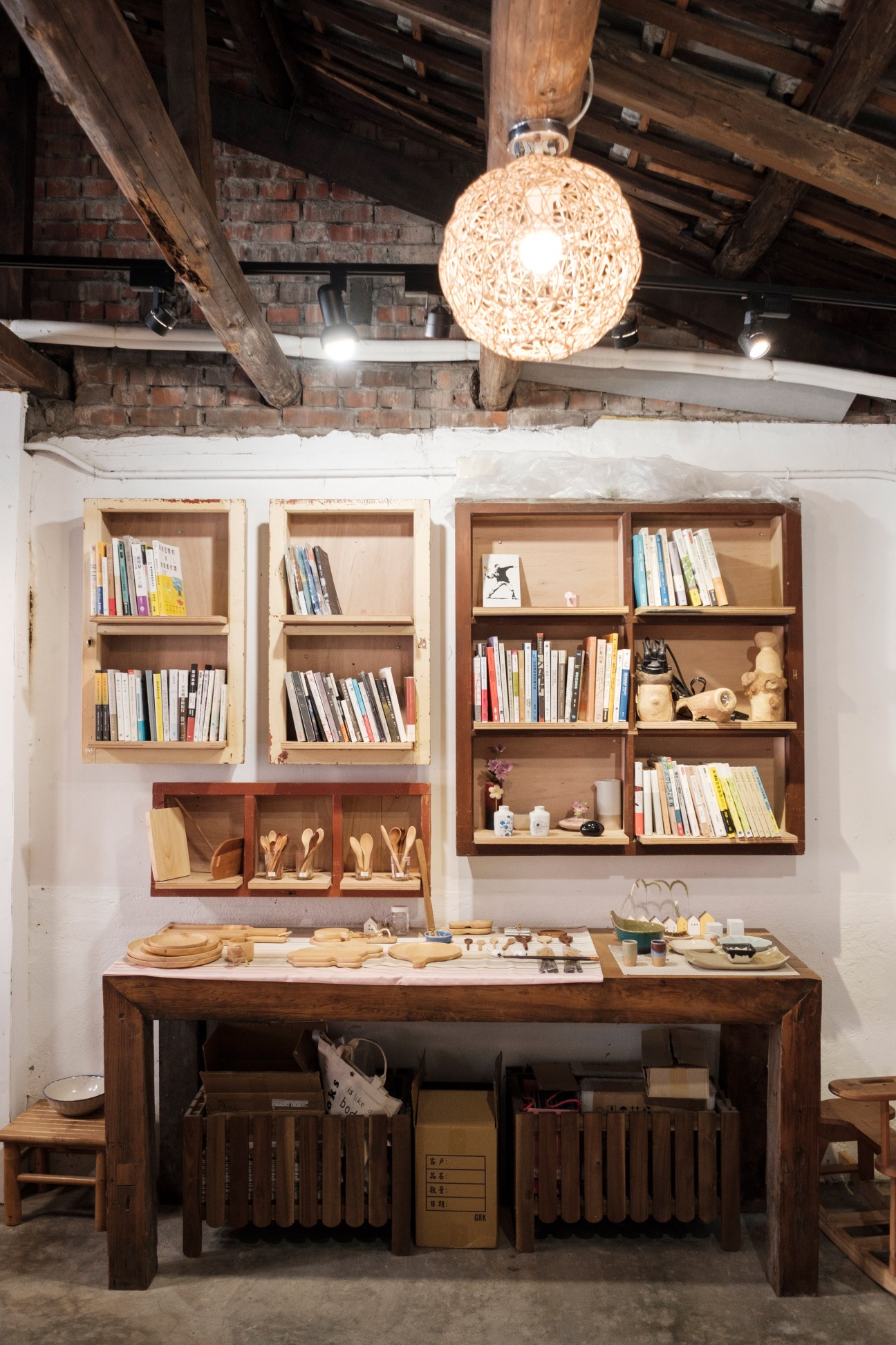 Interior of Stay Traveler Bookstore with wooden shelving, books, crafts and woven pendant light