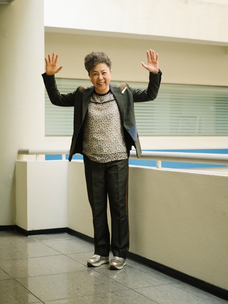 Bonnie Tu, chairwoman of Giant, stands with arms raised in celebration inside a modern office building.