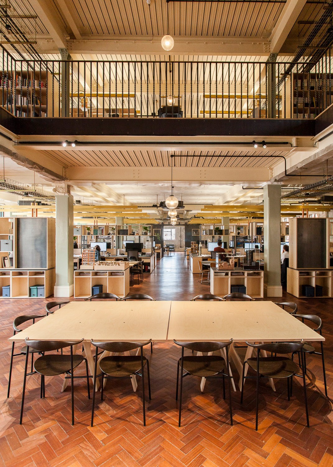 Interior view of Squire and Partners' open-plan office with multiple levels, exposed wooden beams, and contemporary furniture.