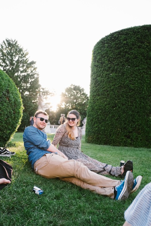 Couple sitting on grass between tall manicured hedges at Kunsthistorisches Museum grounds in Vienna.