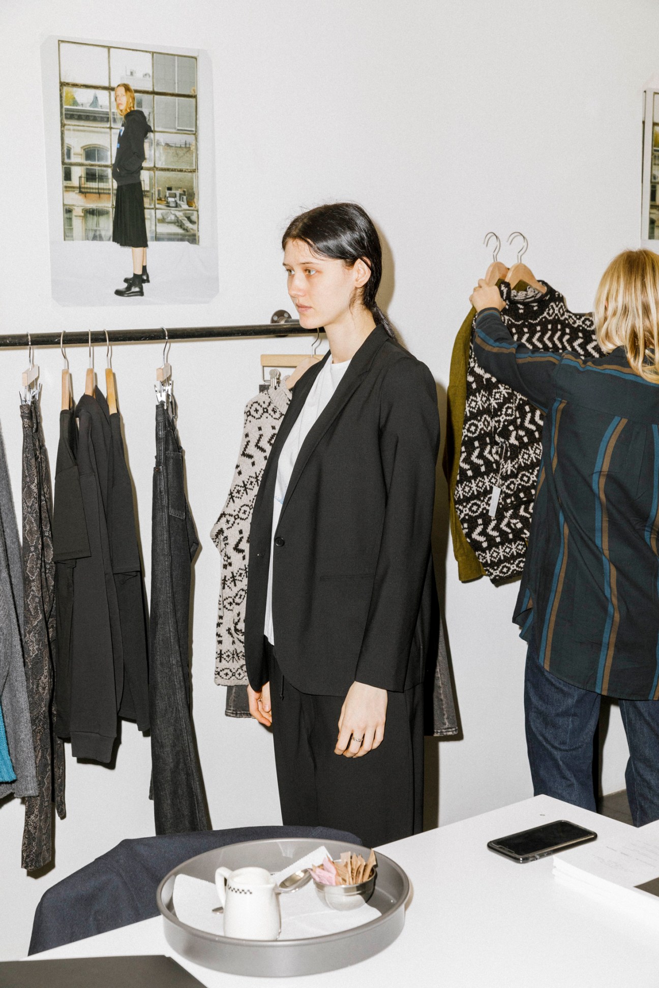 Woman in black blazer standing in fashion showroom with clothing racks