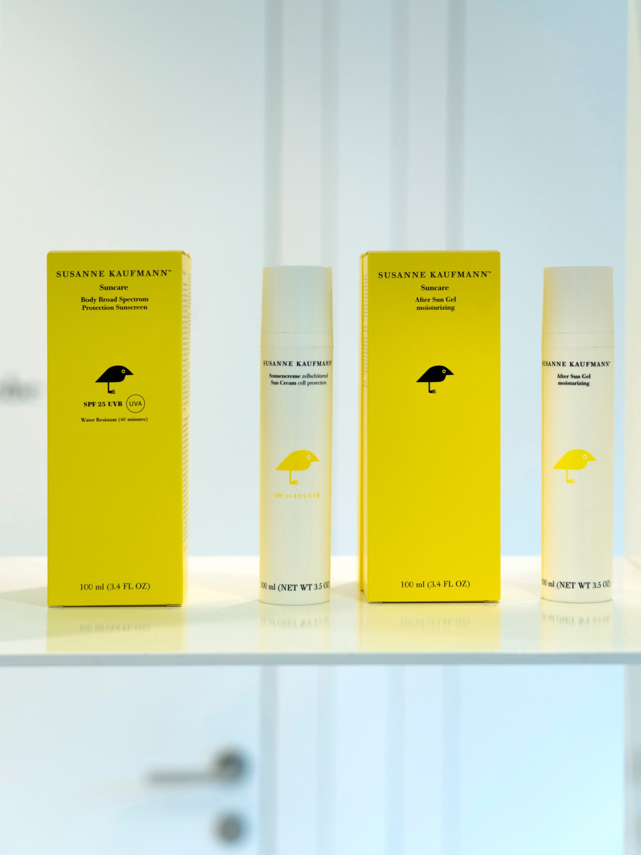 Susanne Kaufmann suncare products with yellow boxes and cream bottles on white surface.