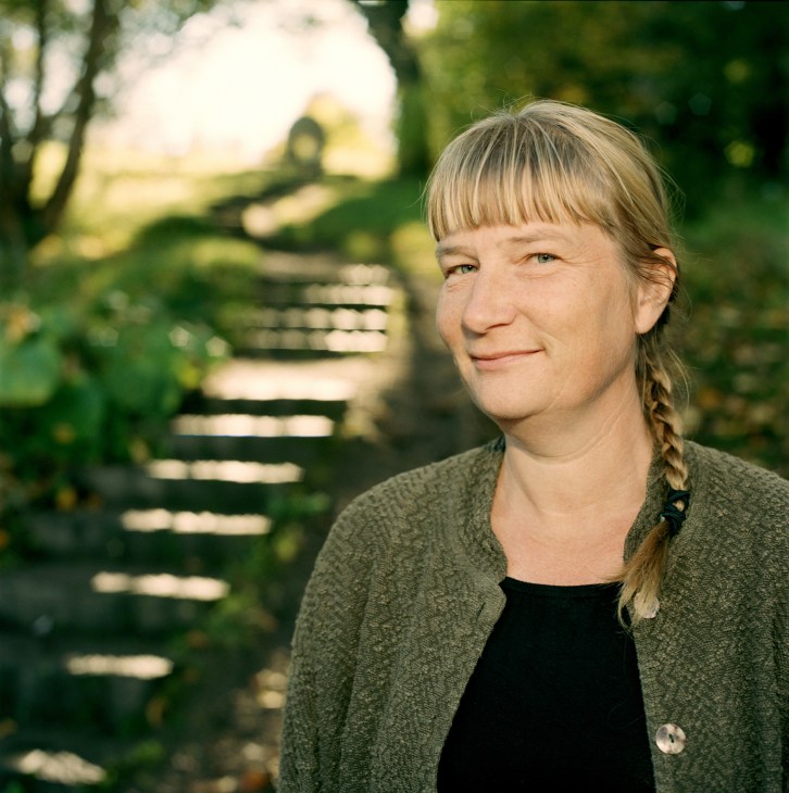 Susanne Wiigh Mäsak, a biologist in a green cardigan, stands outdoors smiling.