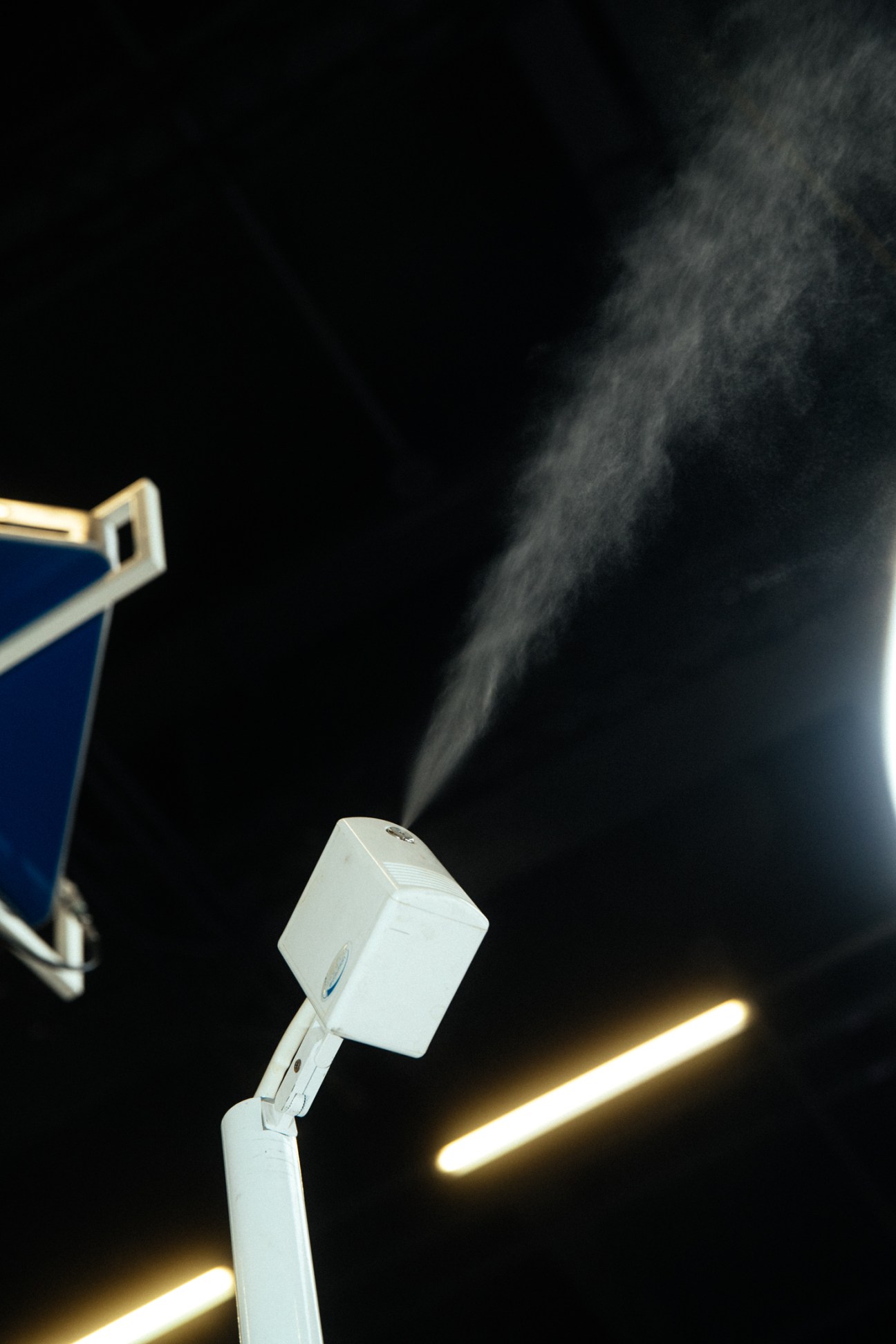 White Condair humidifier device emitting visible mist or vapor against dark background
