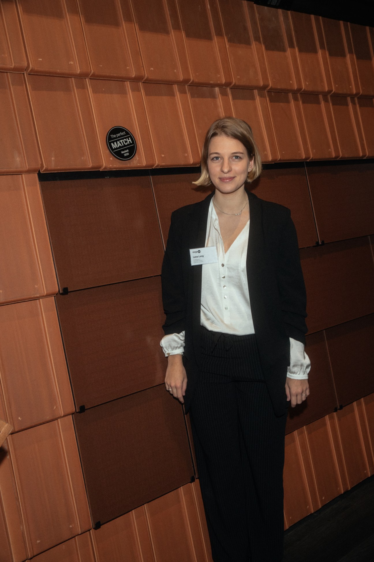 Lena Lang of solar roofing company MegaSo standing in front of orange roof tiles at trade fair