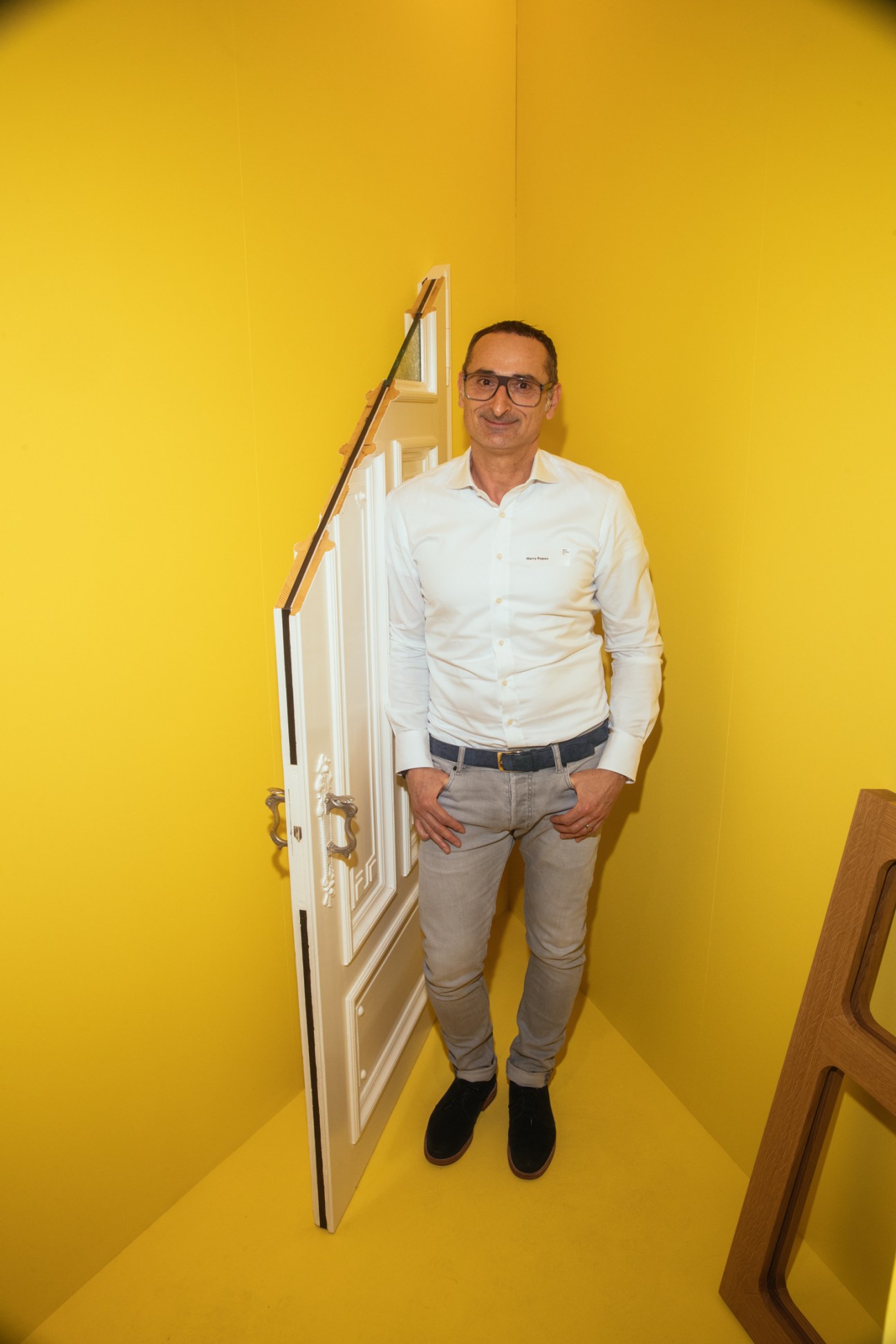Harry Popov stands next to white fire-protection doors in a yellow corner display at a trade fair