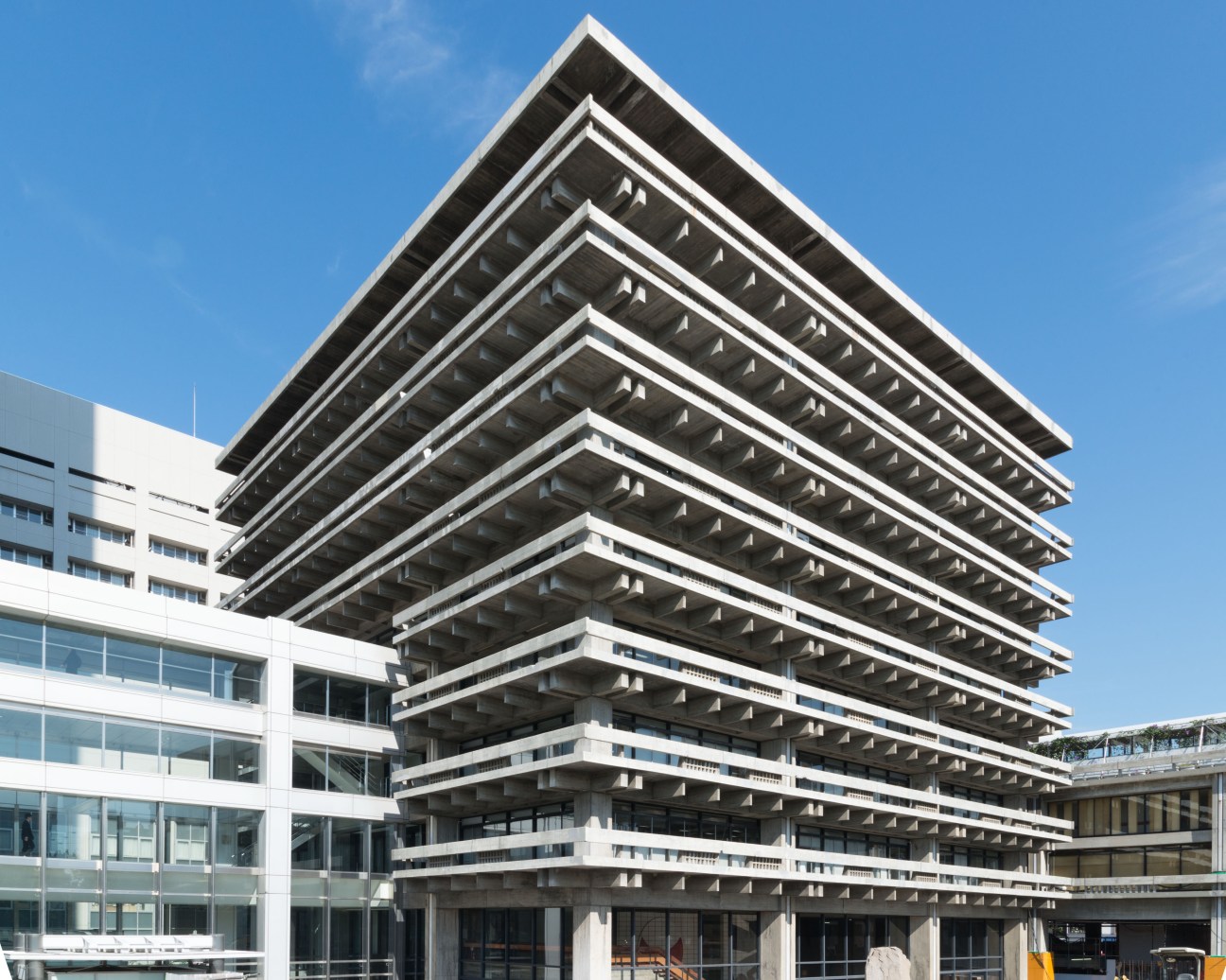 Kenzo Tange's 1958 Kagawa prefectural office building with brutalist concrete beams and modernist architecture against blue sky.