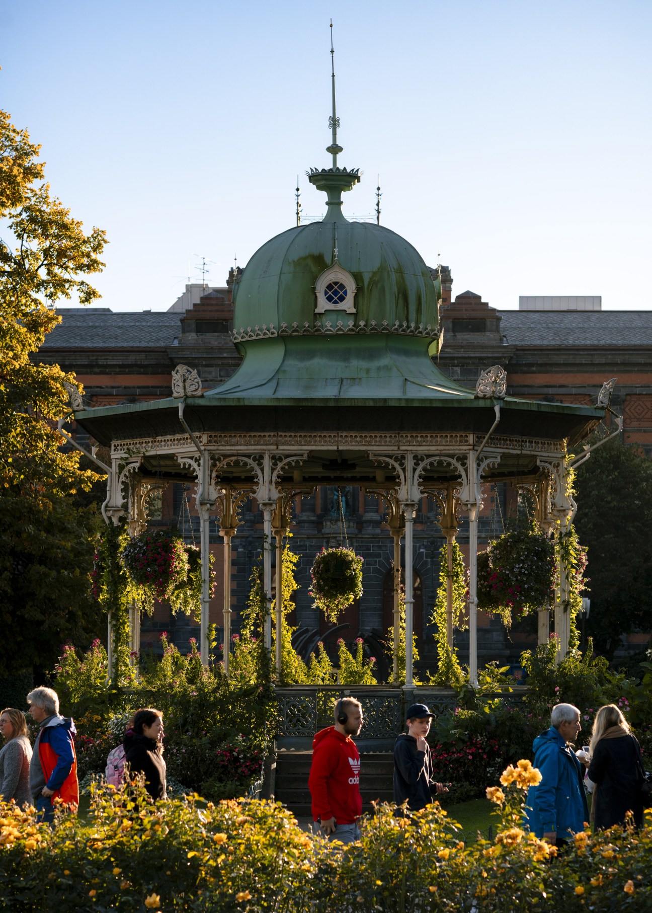Bergen Music Pavilion with its distinctive green copper dome and white ornate colonnade surrounded by autumn foliage and visitors.