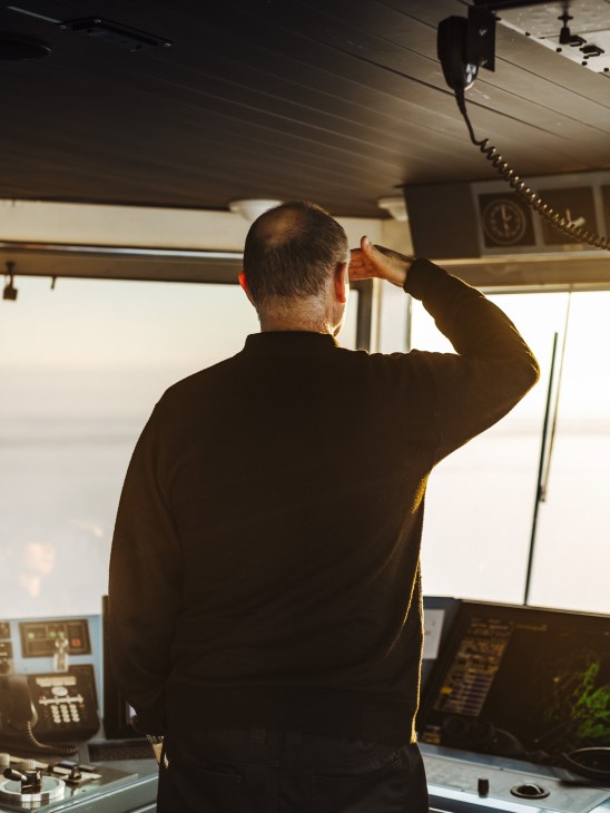A deck officer on the Kontio icebreaker surveying the frozen horizon from the bridge.