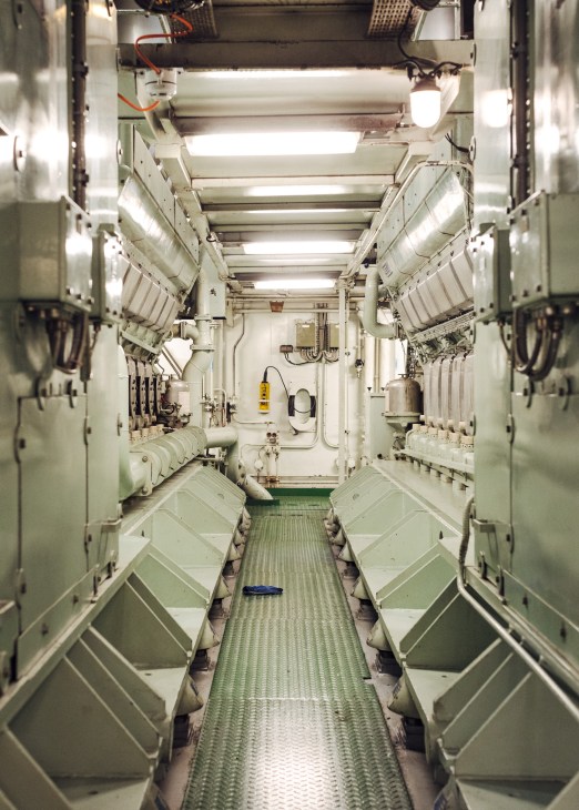 Interior corridor of icebreaker Kontio showing diesel engines, piping, fluorescent lighting and equipment lining both sides.