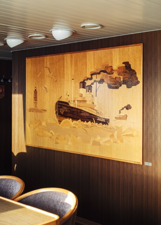 Wood inlay artwork depicting a ship breaking through ice, displayed on the wall of Kontio's meeting room.