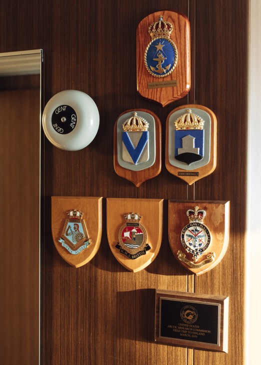 Naval plaques and emblems mounted on wooden wall paneling inside the icebreaker Kontio.