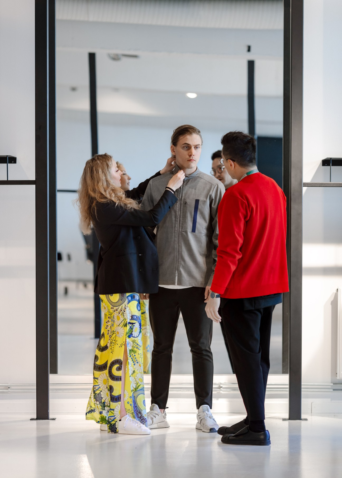 Fashion designers adjust a grey jacket on a male model at Holzweiler studio in Oslo.