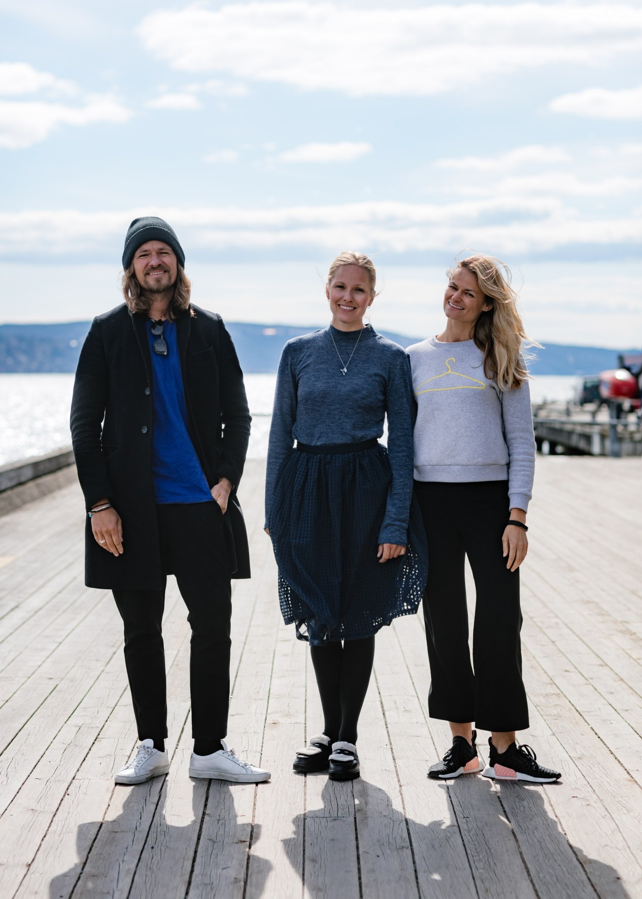 Andreas, Maria and Susanne Holzweiler standing on a waterfront boardwalk with fjord mountains in the background.