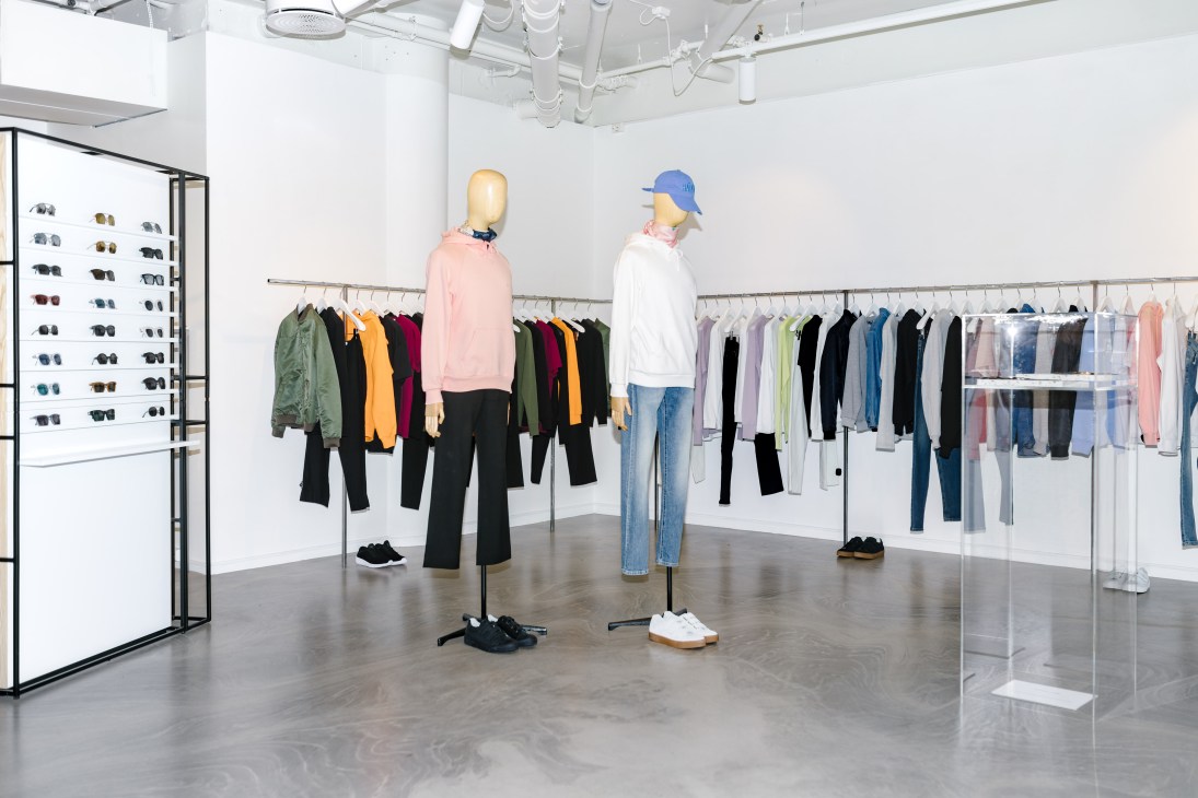 Minimalist retail interior at F5 fashion shop displaying mannequins in colorful clothing and eyewear on walls.