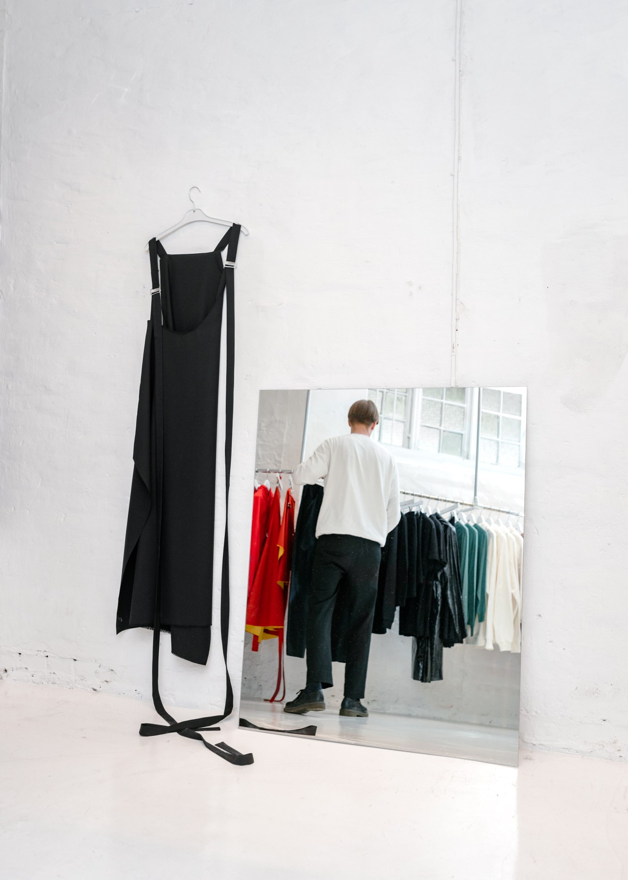 Black sleeveless dress on hanger displayed next to mirror showing fashion retail interior at Avenue boutique.