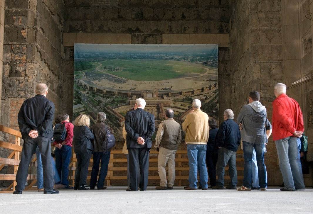 Tourists viewing an aerial photograph of Tempelhof airport displayed inside the historic terminal building.