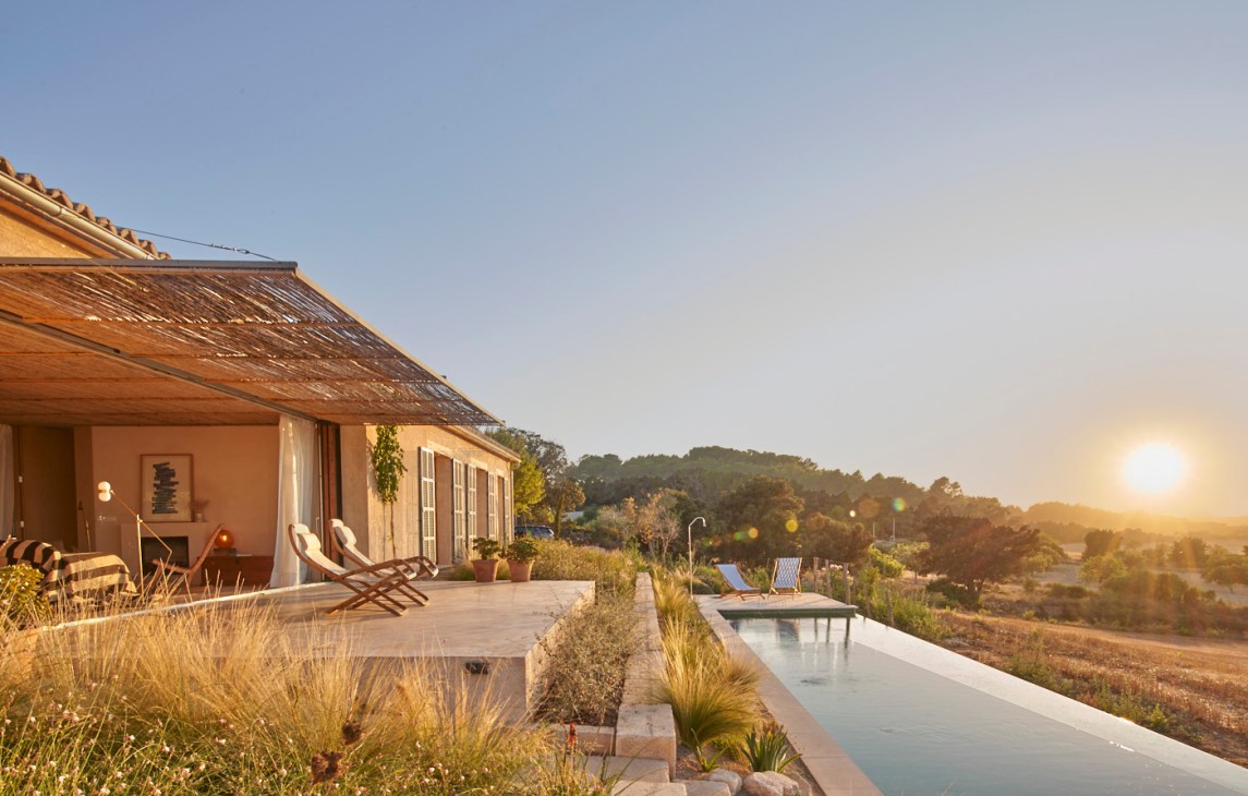 Terrace with pair of mid-century bamboo loungers overlooking countryside at sunset