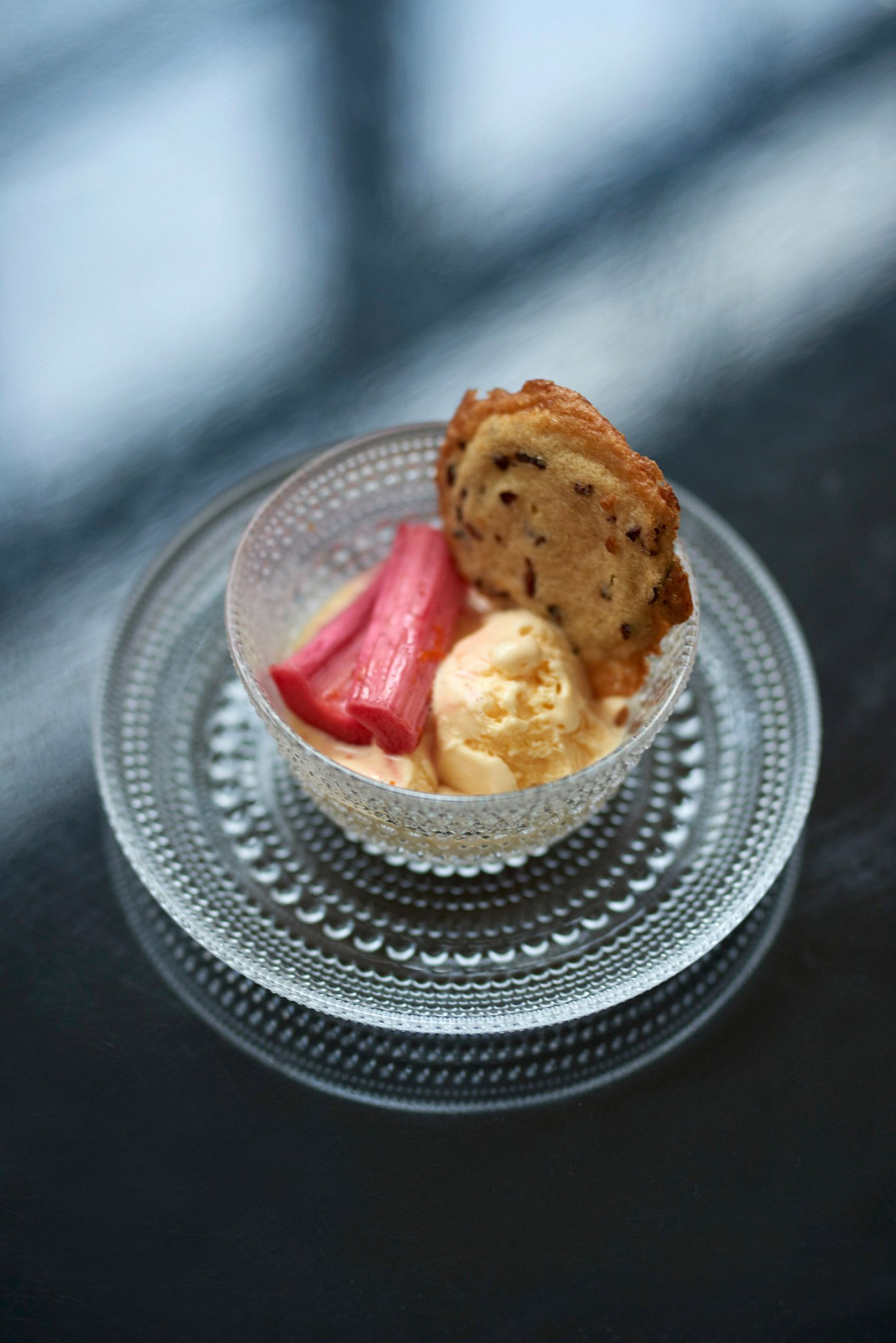 Buckwheat cookie with roasted rhubarb and crème fraîche ice cream on a decorative plate.