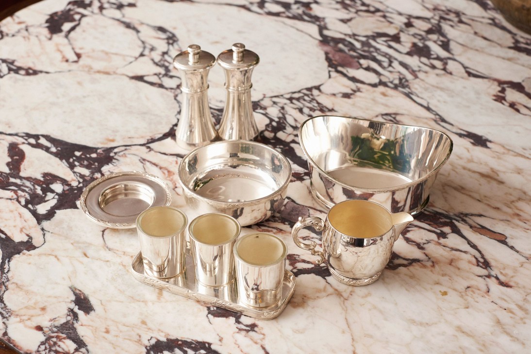 Silver tableware and condiments arranged on a marble surface at Kettner's restaurant.