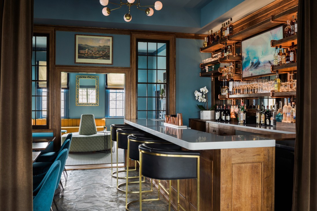 The Clifton's copper bar and lounge with blue velvet seating, wooden shelving, and brass fixtures.