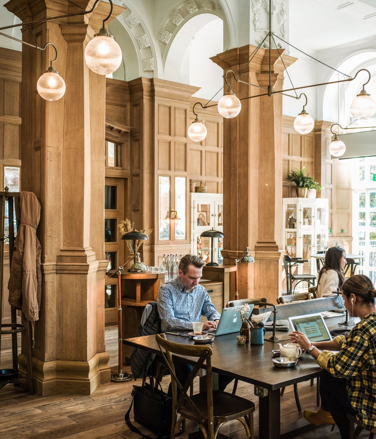 Burr & Co coffee shop at The Principal hotel with wood panelling, pendant lights and customers working at tables.