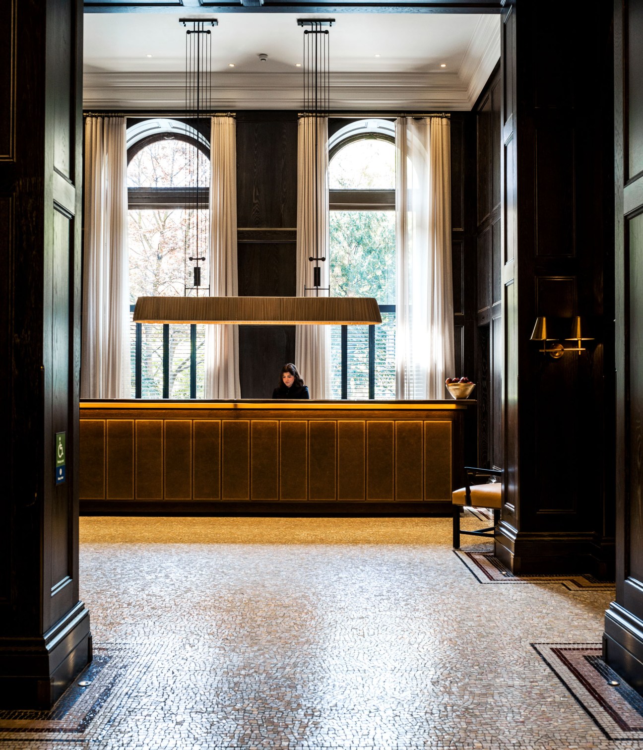 The Principal hotel's tiled lobby with mosaic floor, wood-paneled reception desk, and tall arched windows.