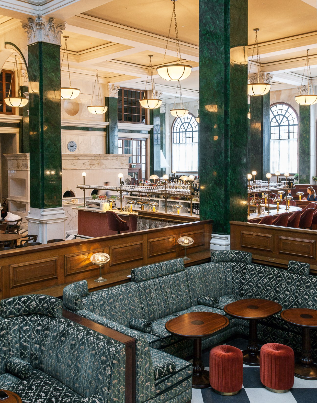 The Ned's Nickel Bar with green marble columns, pendant lighting, and upholstered seating overlooking Cecconi's restaurant.