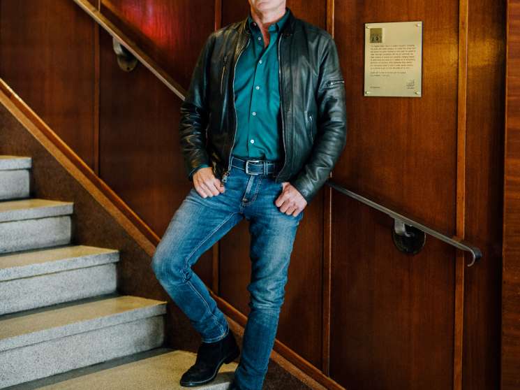 Jeff Stober, founder of the Drake Hotel, standing on wooden stairs against a wood-paneled wall.