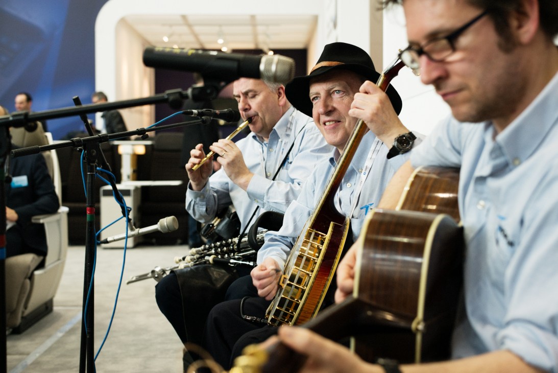 Traditional Irish band performing with instruments at Aircraft Interiors Expo booth