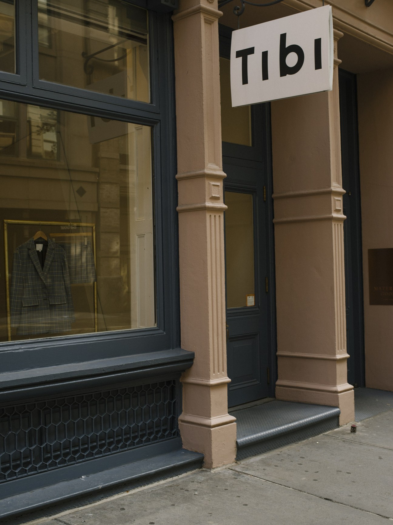 Tibi flagship store exterior on Wooster Street with white sign and navy storefront