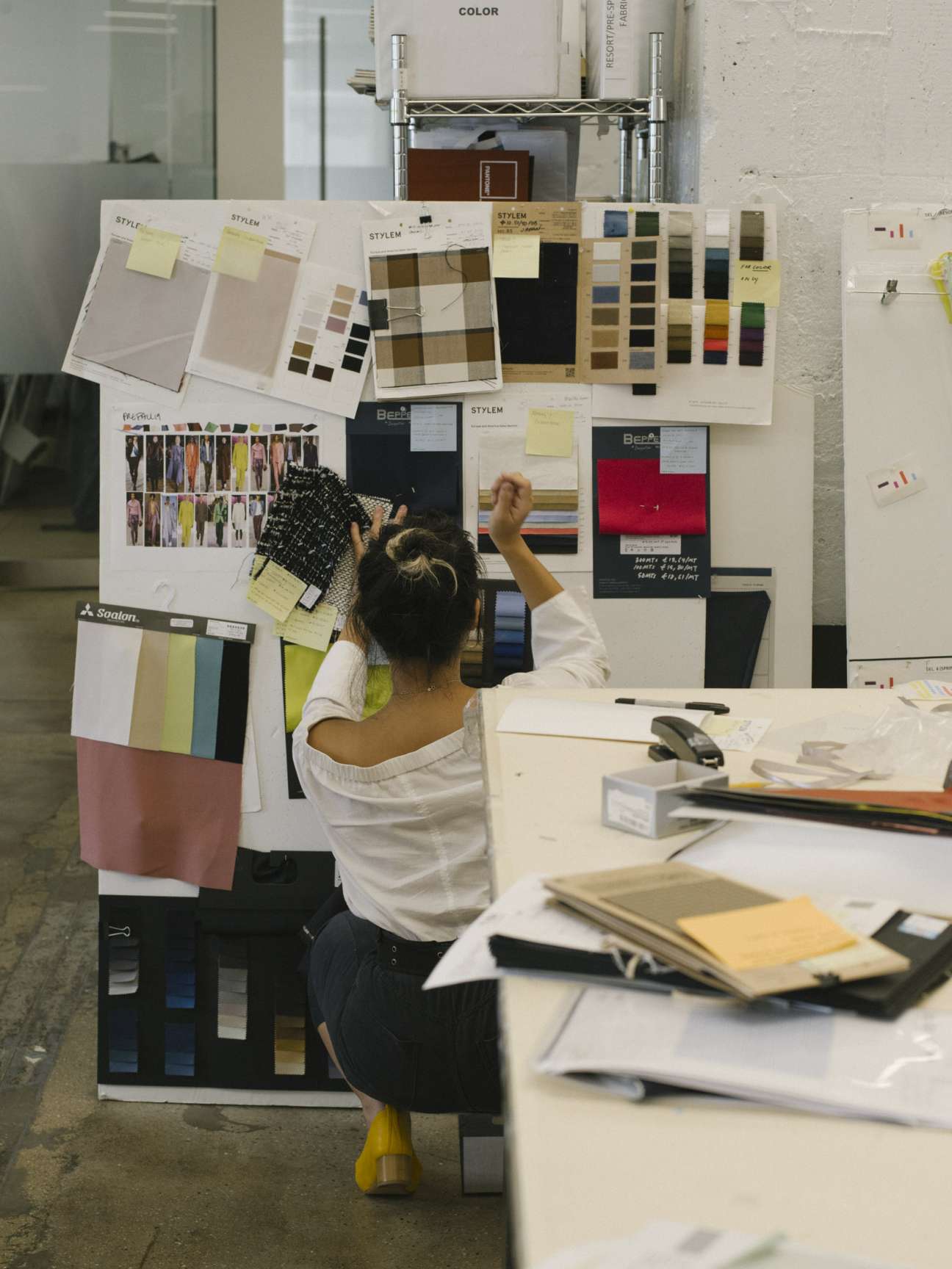 Designer comparing fabric color swatches on a mood board in studio workspace.
