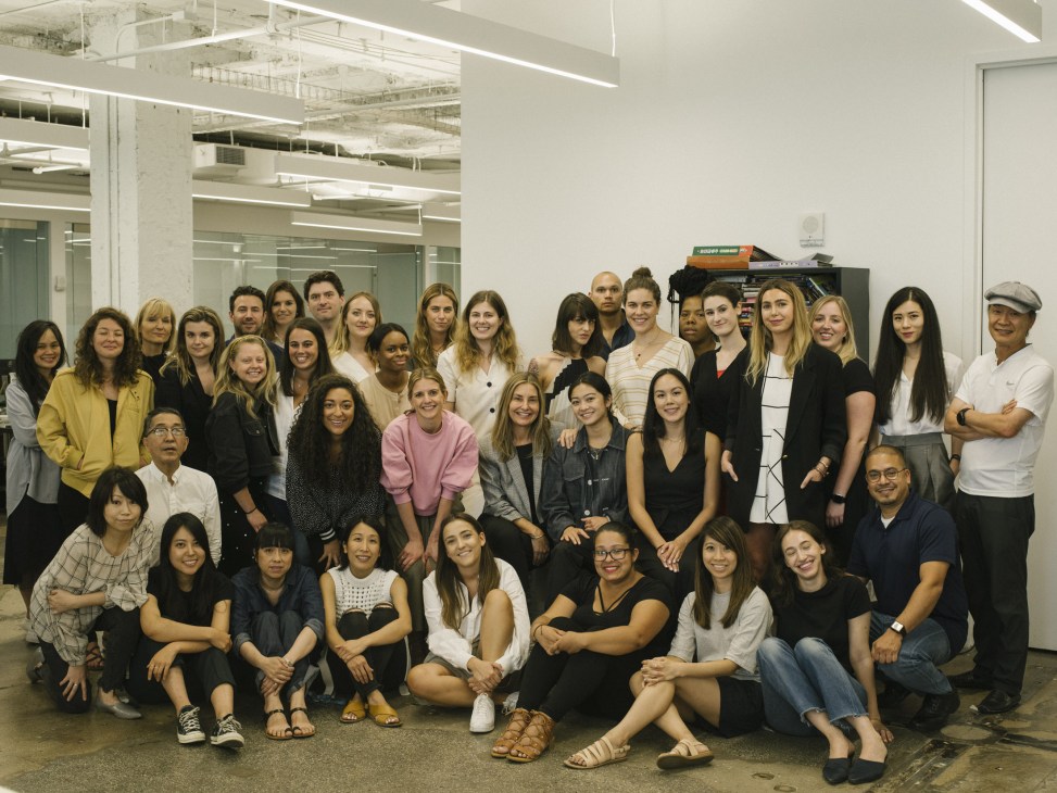 Group photo of approximately 40 Tibi studio staff members posed together in a modern office space in New York.