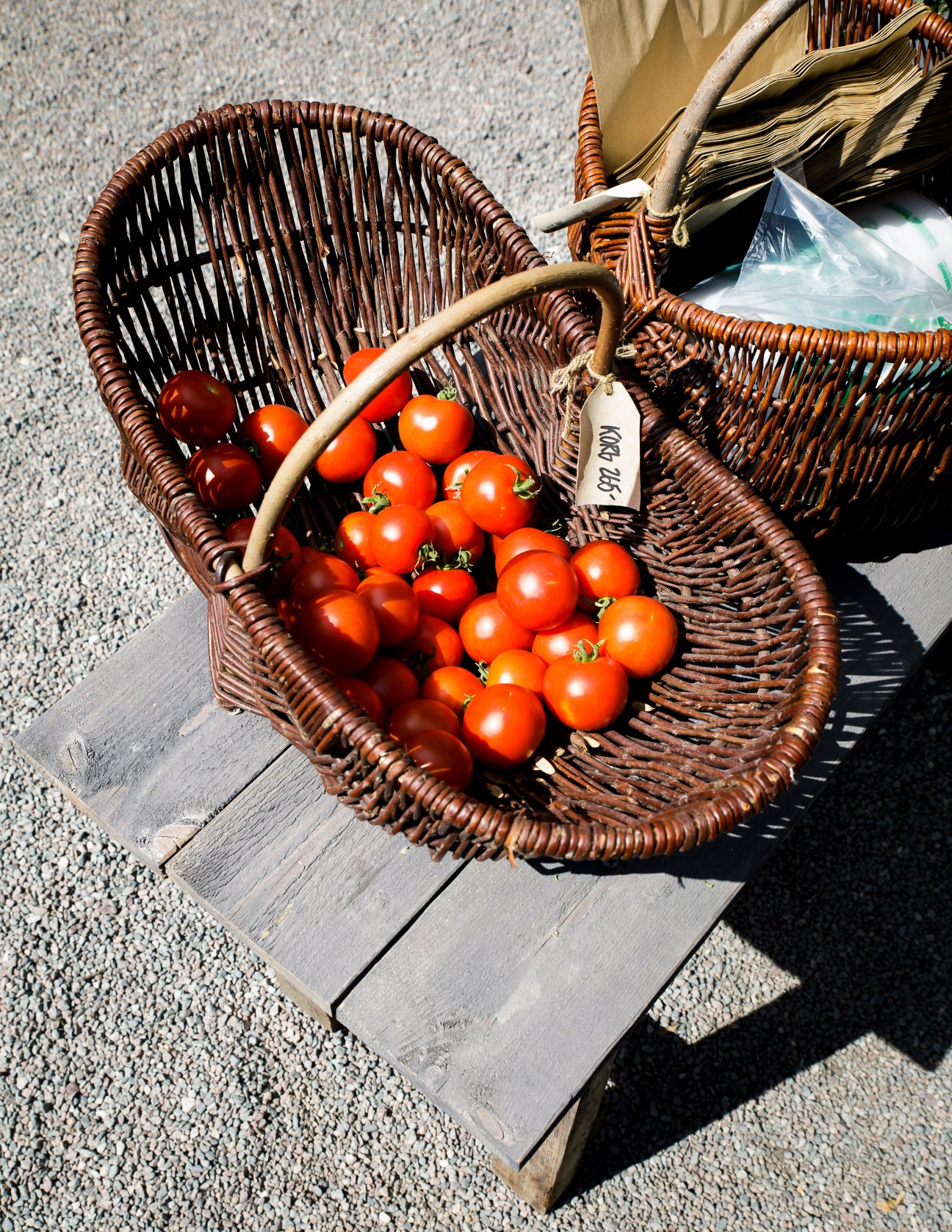Fresh red tomatoes in wicker baskets with price tags at an outdoor market