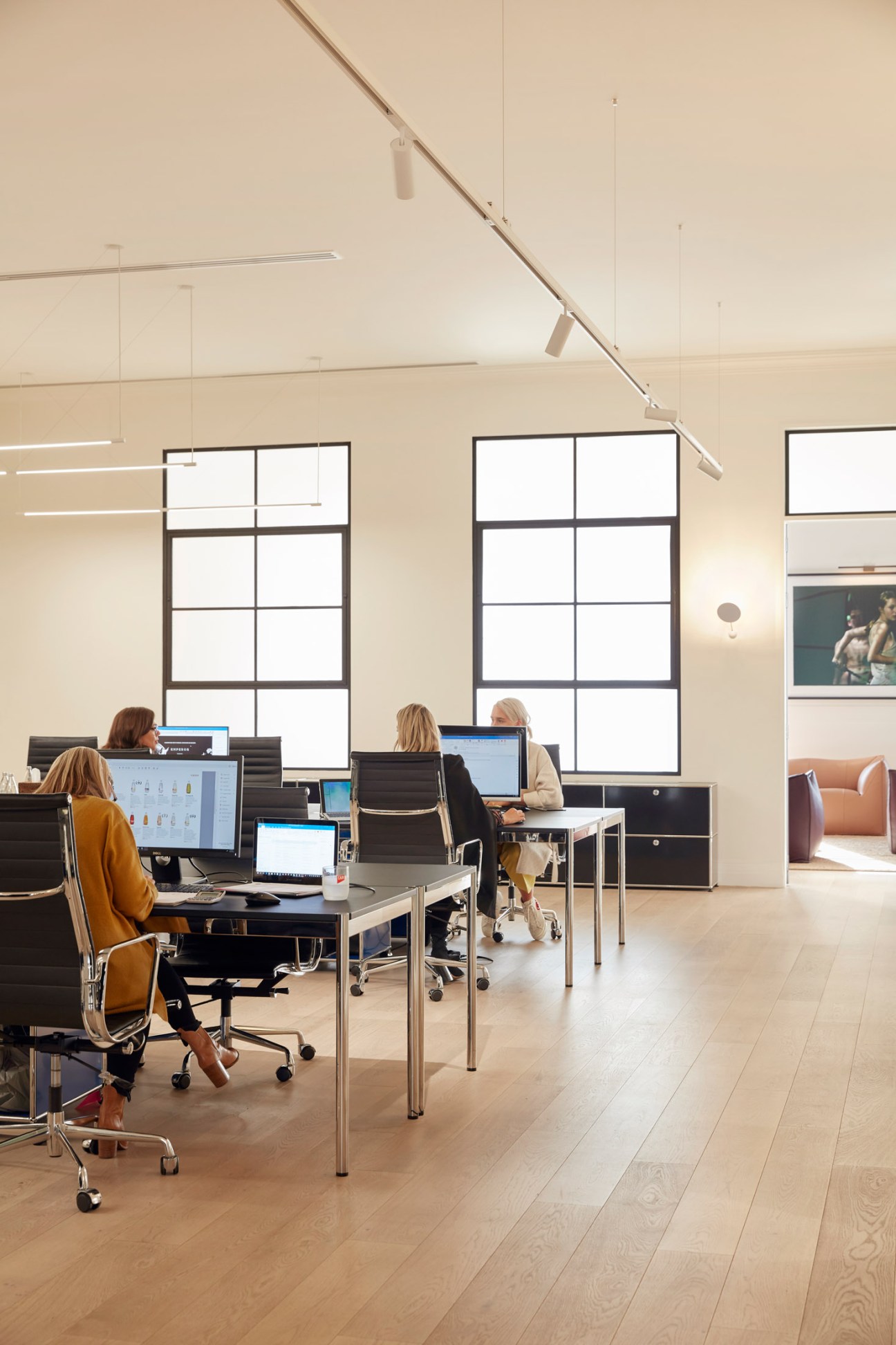 Capi headquarters open-plan office with employees working at desks with computers and large windows.