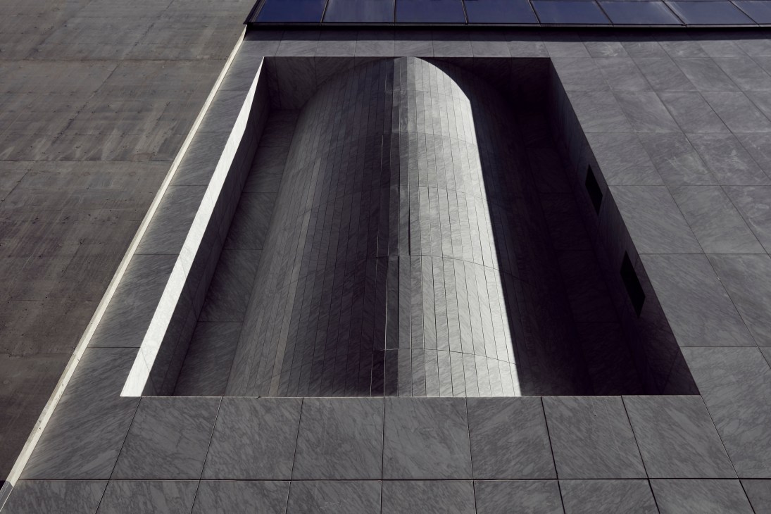Eporo Tower's lower façade showing a recessed architectural detail with vertical ribbed metal paneling and white linear lighting.