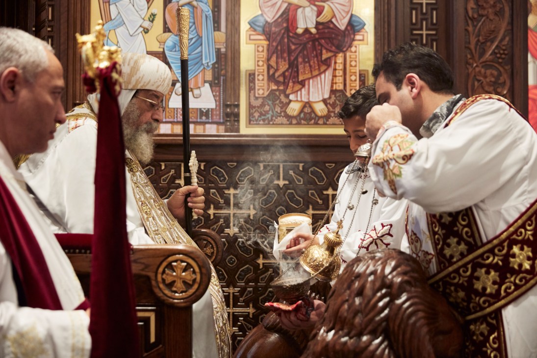 Pope Tawadros II leads a liturgy at the Church of Saint Verena and Saint Bishoy, holding a ceremonial staff before iconographic artwork.