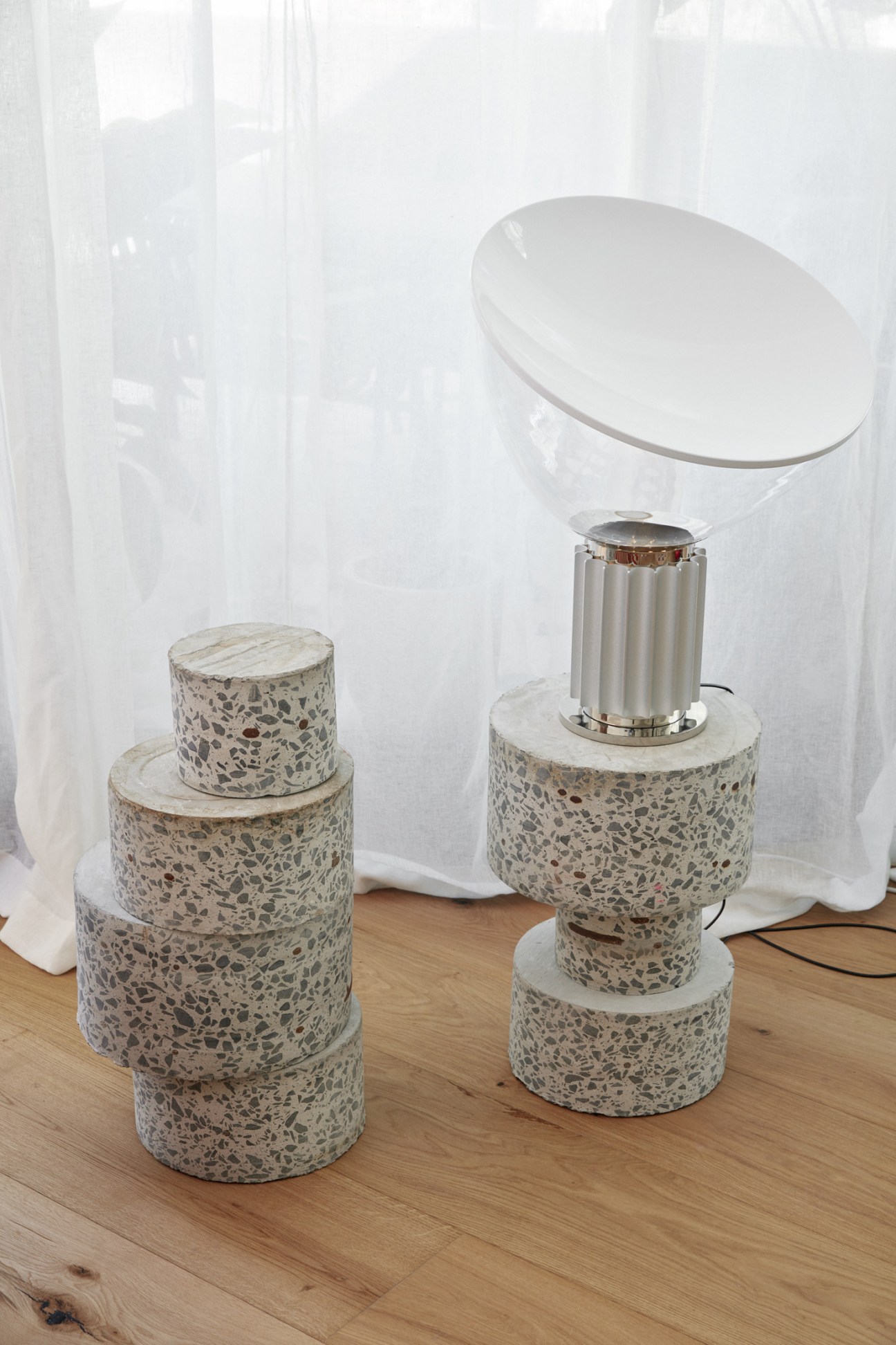 Castiglioni Taccia lamp with white dome shade on terrazzo base in modern interior setting.
