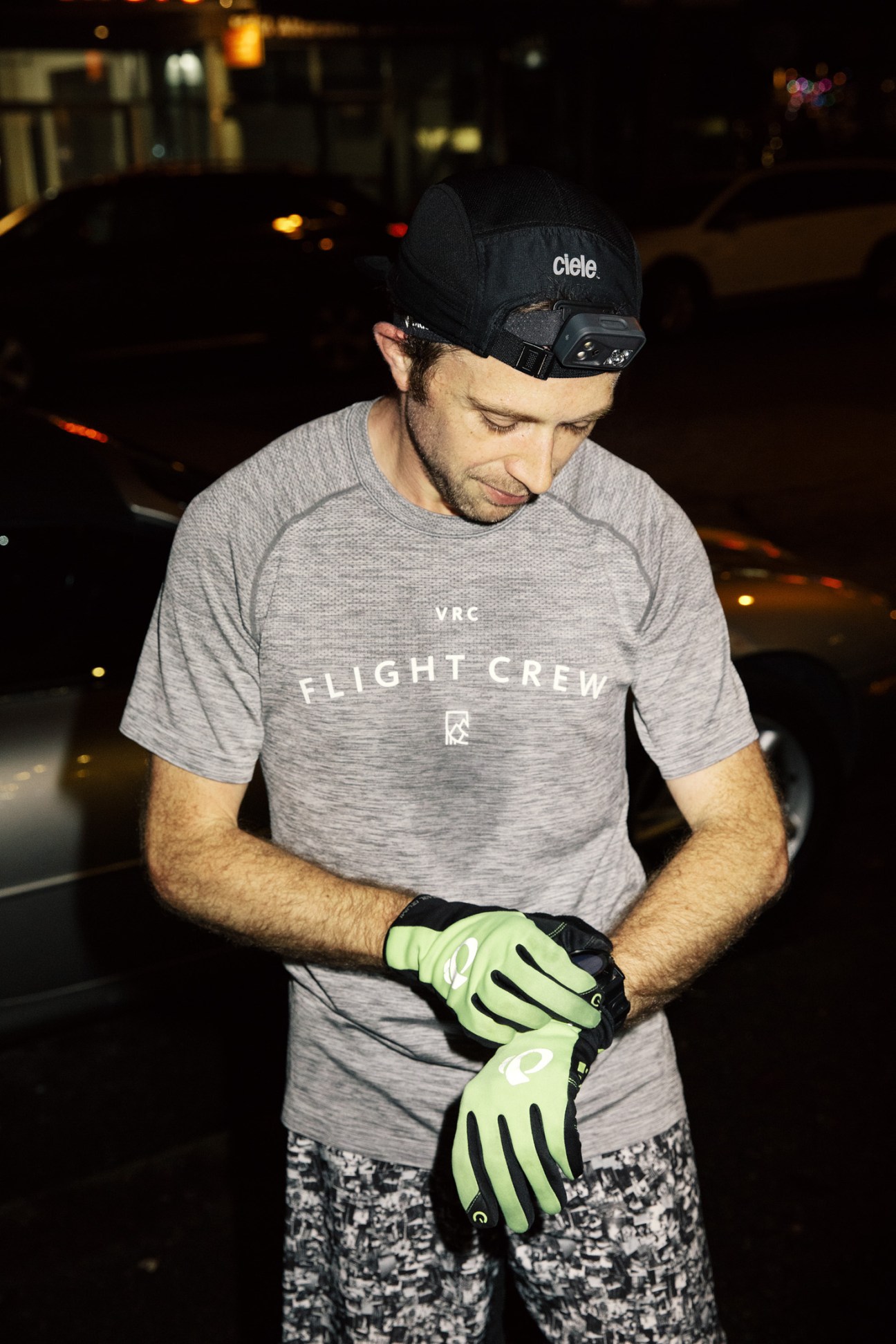 Runner wearing Flight Crew shirt and Ciele cap checks fitness watch during evening run.