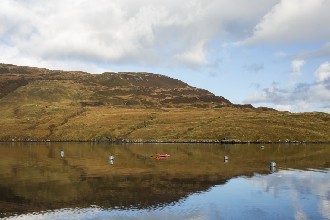Moored boats on Loch Sligachan with rolling hills and moorland behind, where David and Ben Oakes farm scallops.