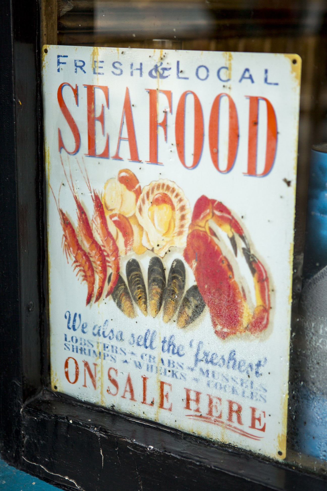 Vintage weathered seafood sign advertising fresh local scallops, lobsters, and crabs for sale.