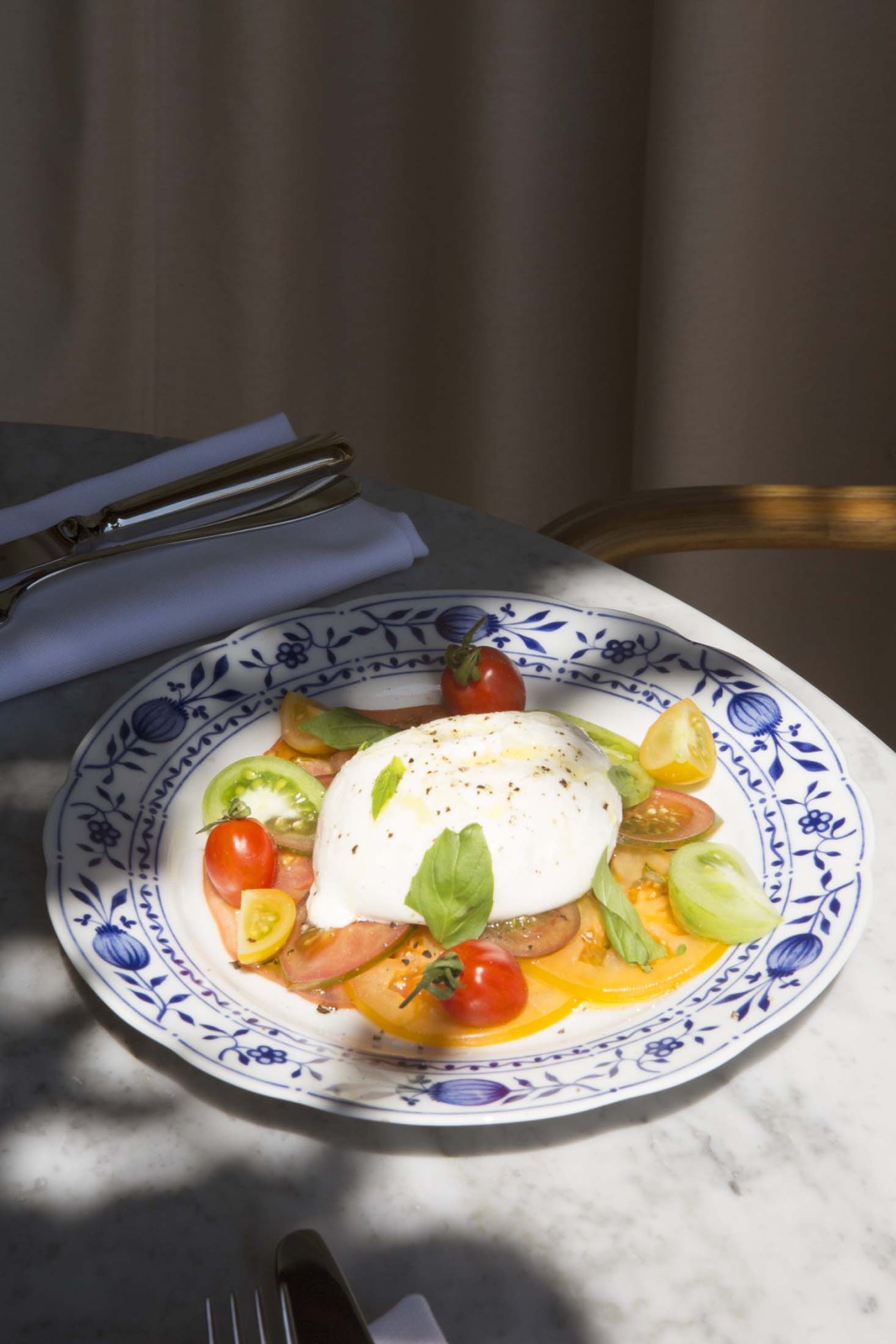 A plate of fresh ingredients displayed on blue and white porcelain tableware.