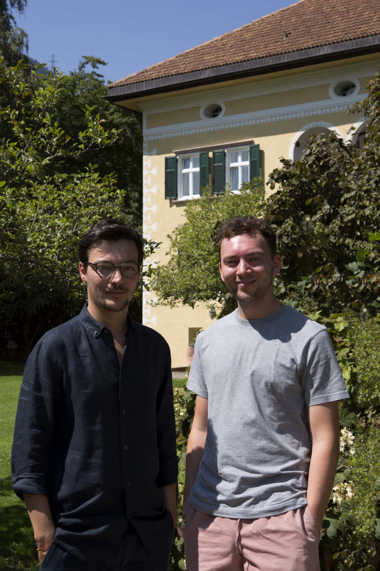 Brothers Klaus and Moritz Dissertori standing in front of Villa Arnica's cream-colored facade with green shutters